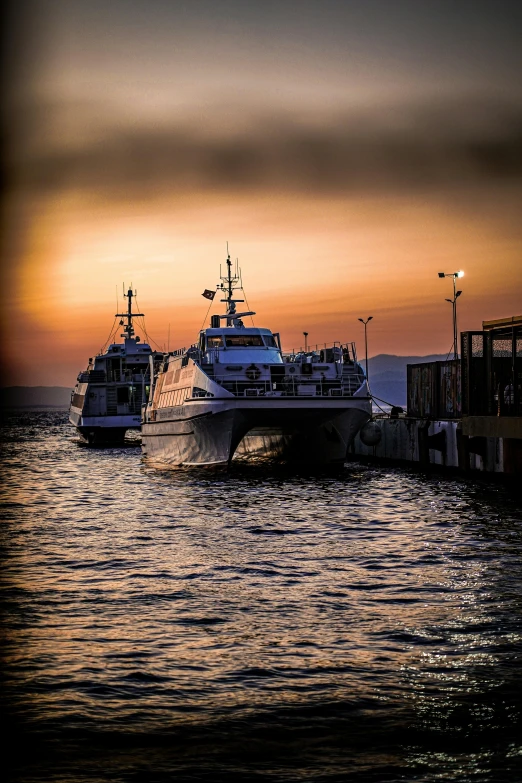 two boats floating on the ocean near a pier