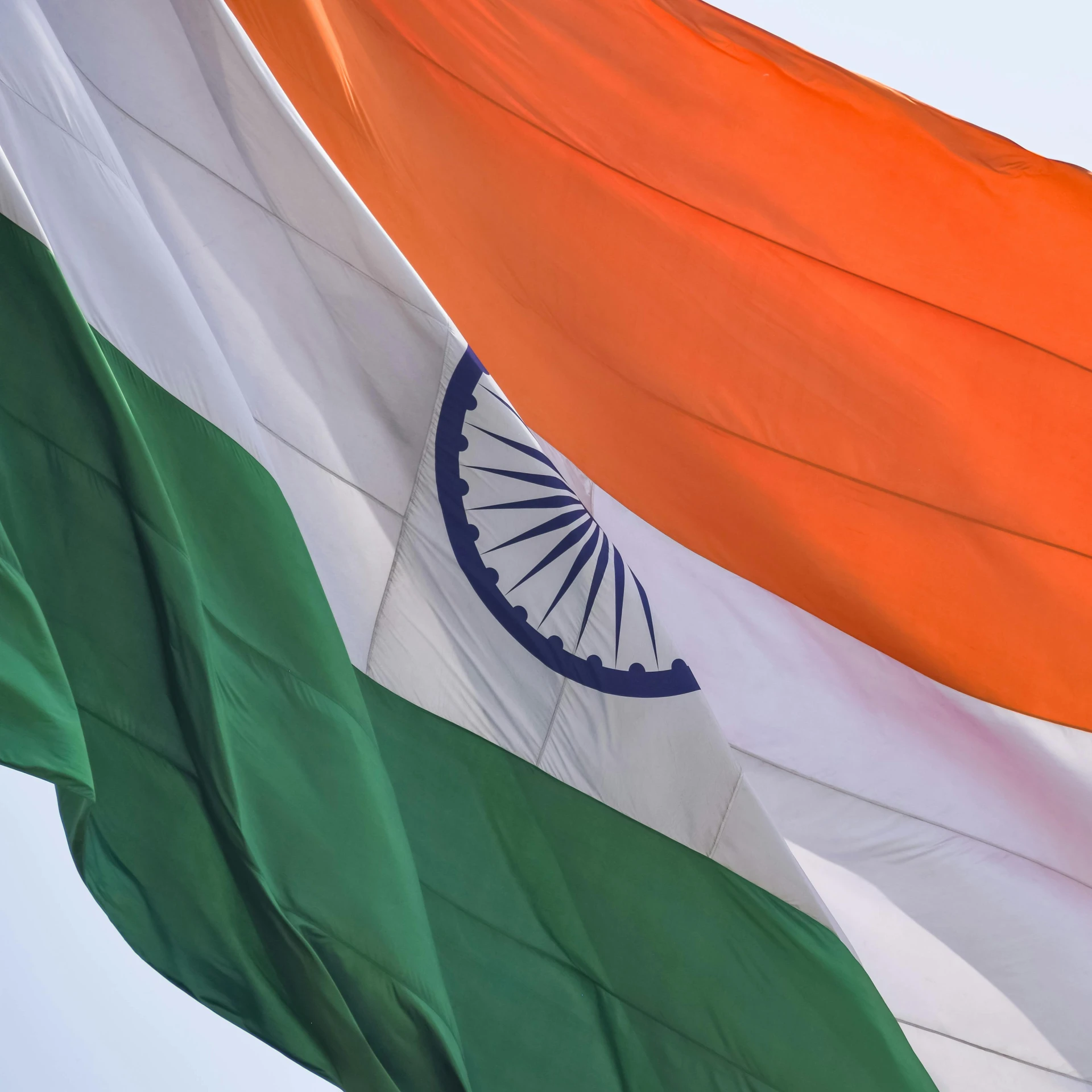 the indian and irish flag fly together in a blue sky