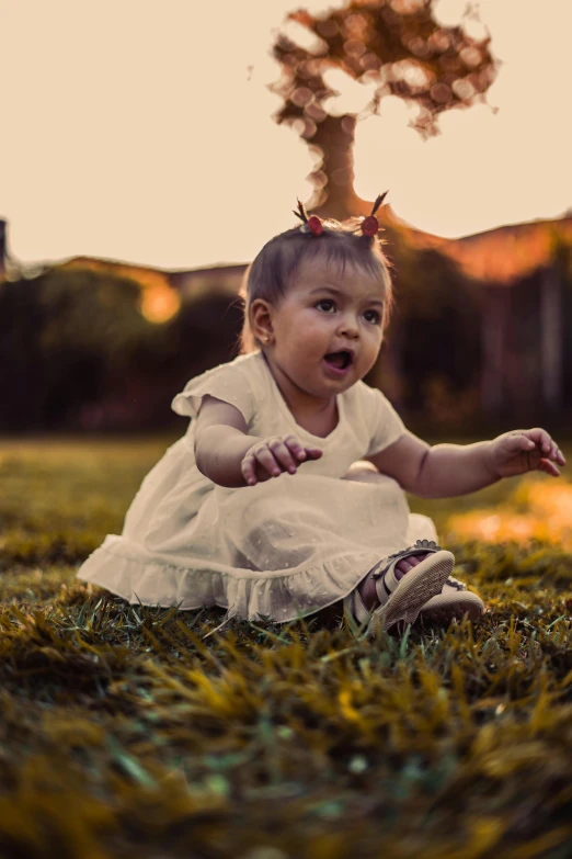 a little girl is sitting in the grass