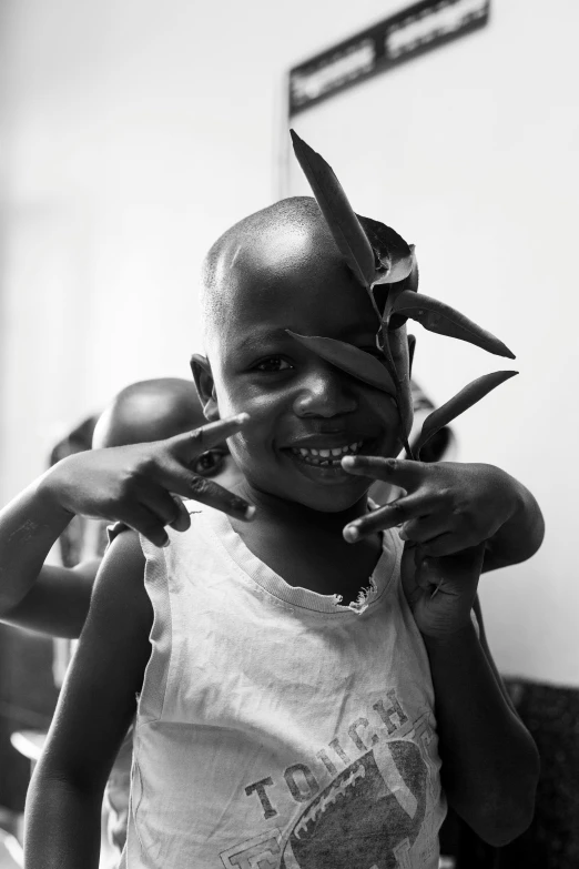 a child is holding soing with fingers and wearing a t - shirt