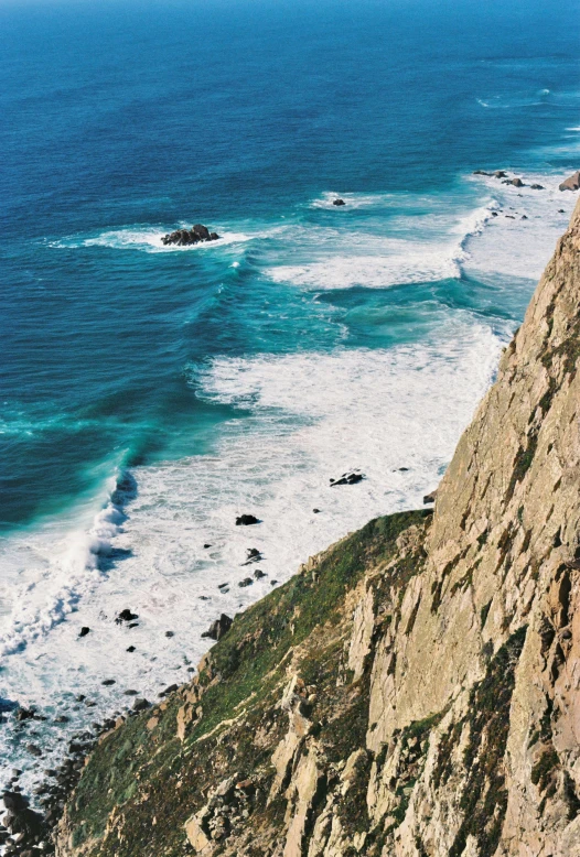 a person looking over a cliff at a body of water