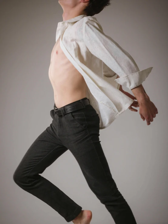 a man standing in front of a grey background, with his shirt open