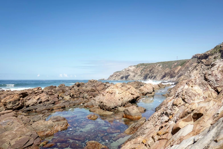 a rocky beach near the shore under a blue sky