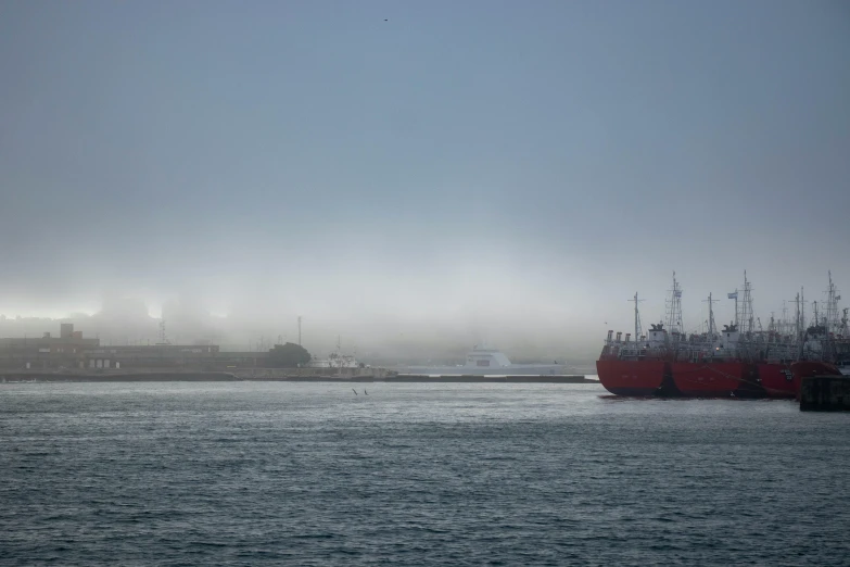 several large boats on a river in the fog