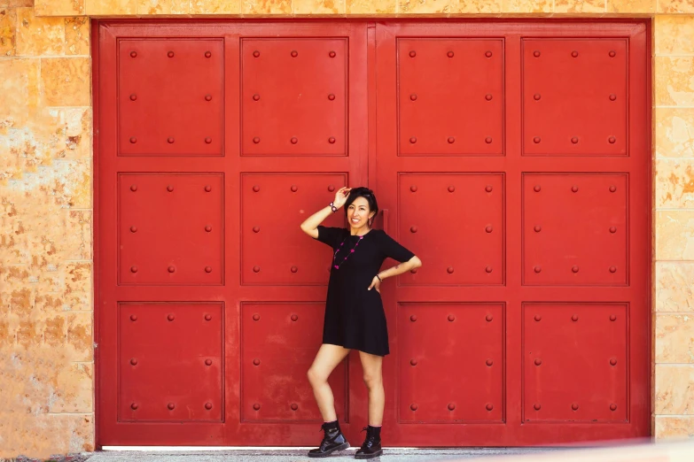 woman posing by large red garage door for picture