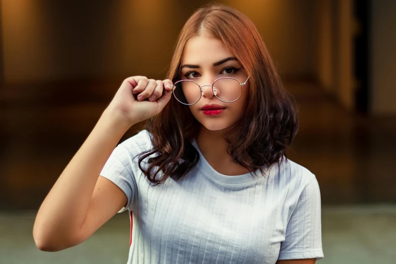 a woman holding a pair of glasses looking at the camera