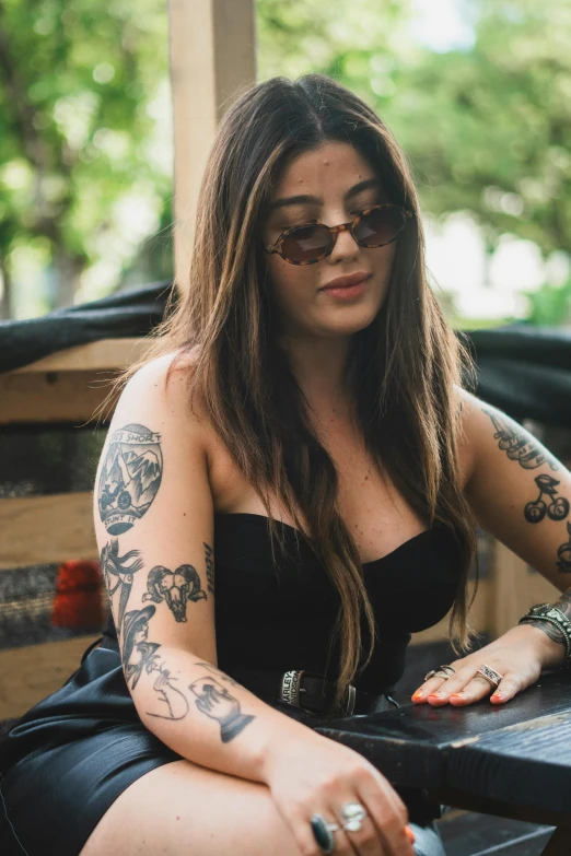 a woman with long hair and tattoos sitting on a bench