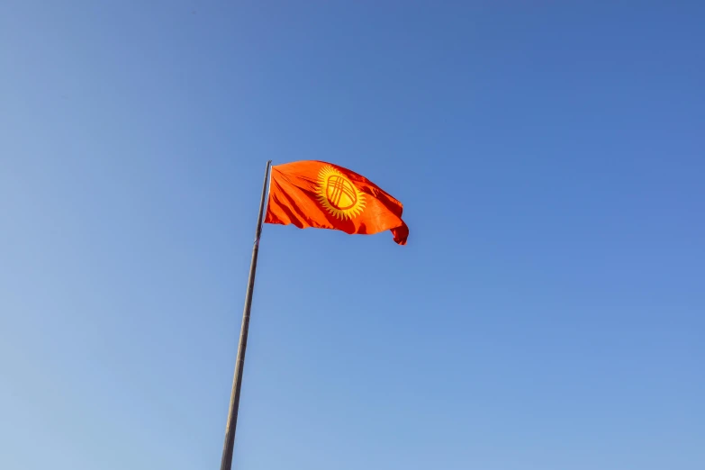 red, orange and gold flag flying high in the sky