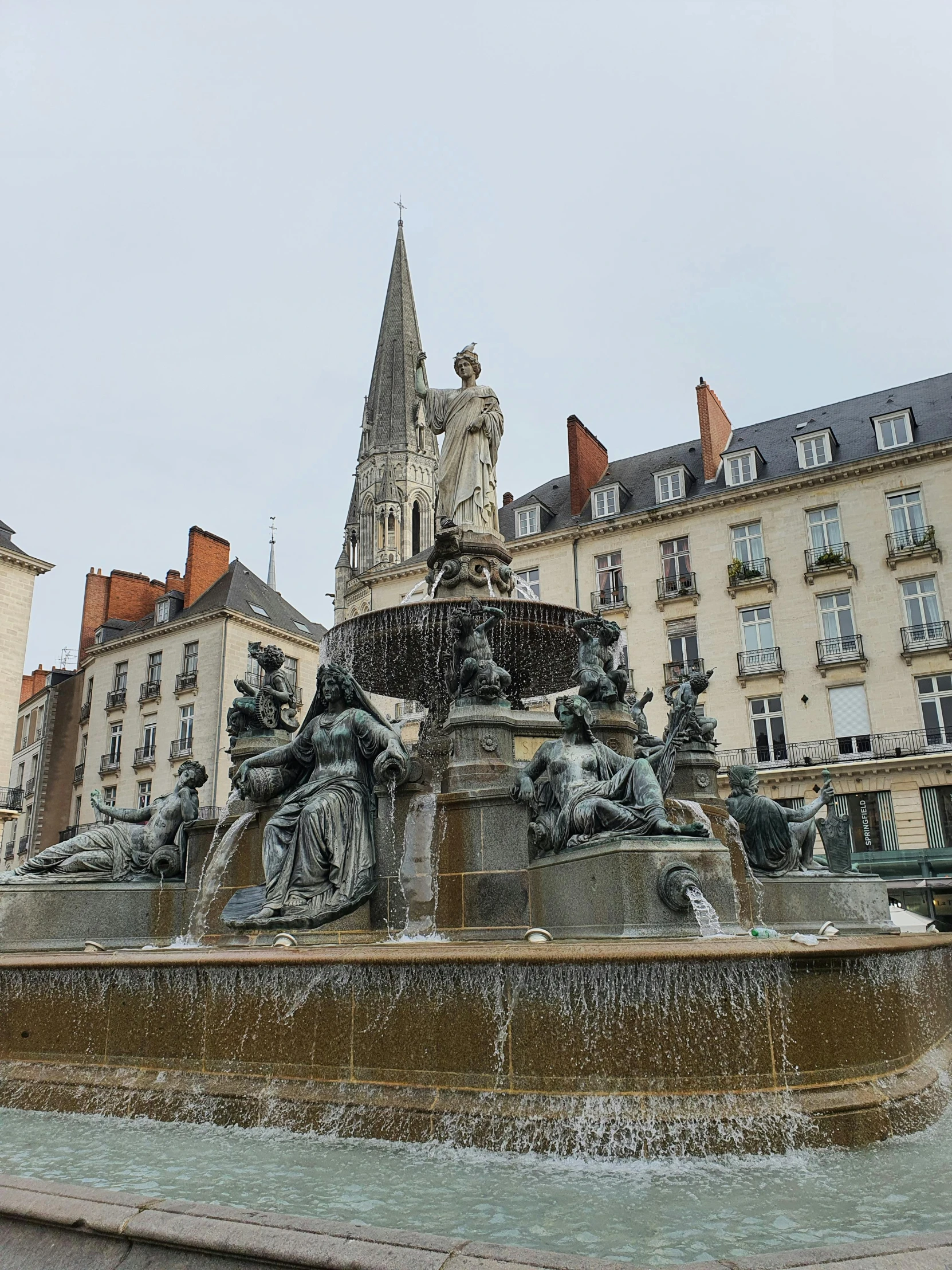 a fountain in front of several buildings with a clock tower