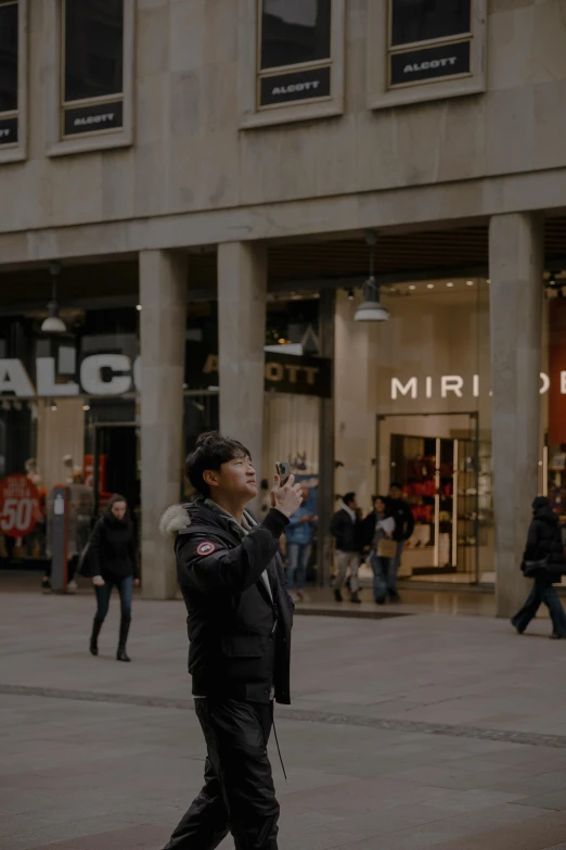 an asian man standing in front of a mall