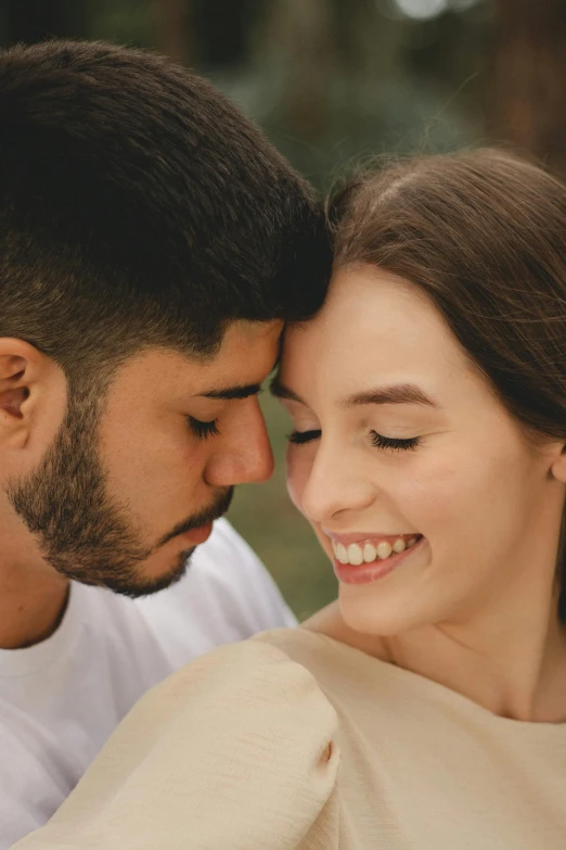 a man and woman smile as they stand close together