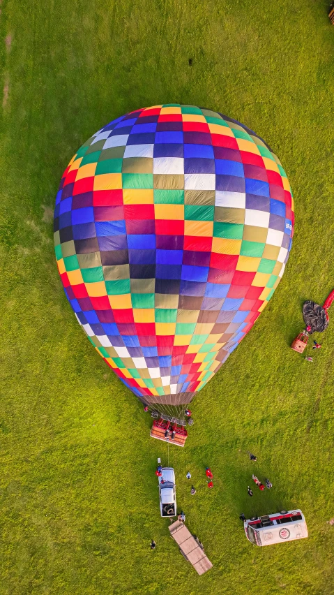 a colorful  air balloon in the sky above people on a field