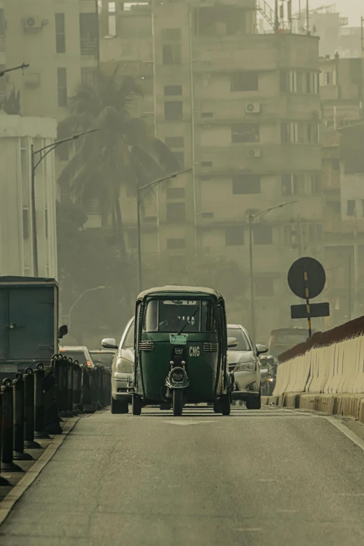 a green bus with headlights is going down the street