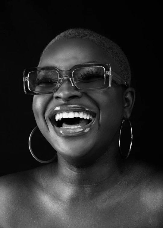 a woman wearing glasses laughing and smiling