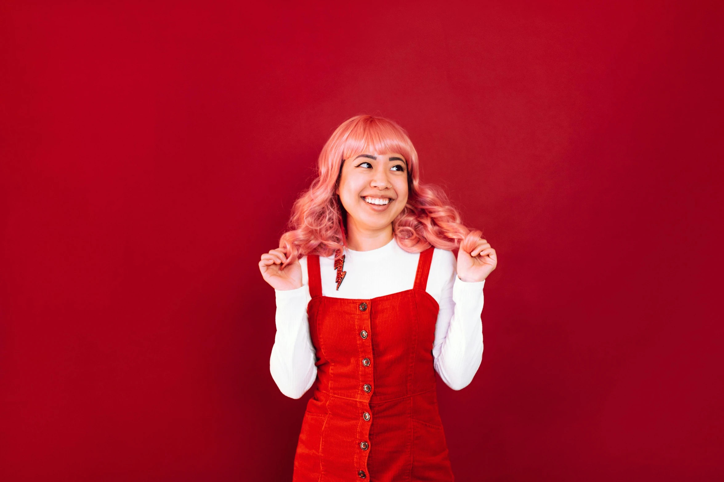 a woman with pink hair wearing an orange overall