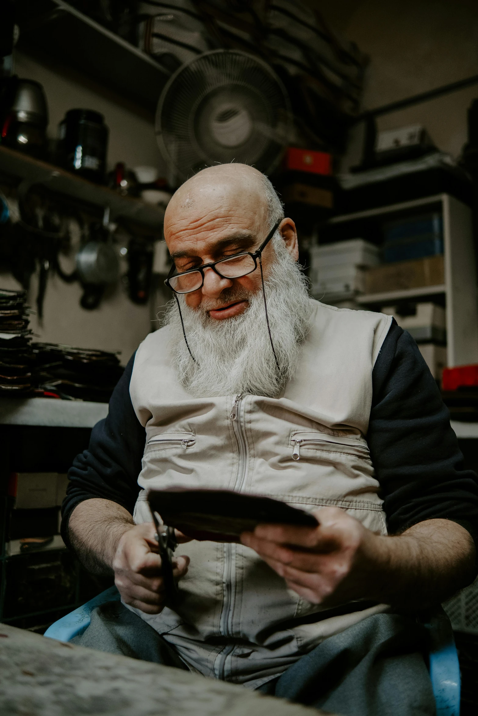 an older man wearing glasses and a balding head sits at a table with a tablet