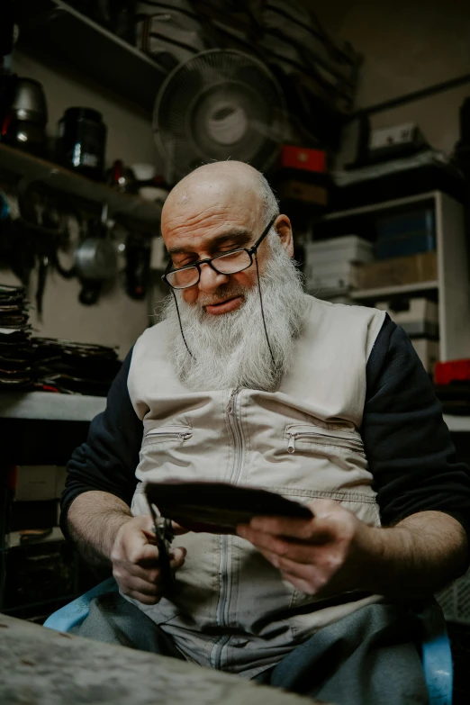 an older man wearing glasses and a balding head sits at a table with a tablet