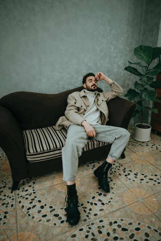 man in trench coat sitting on a brown couch