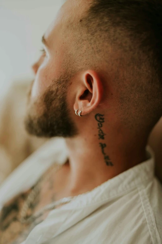 a man is wearing a small ear piece and has a name tattoo on the top