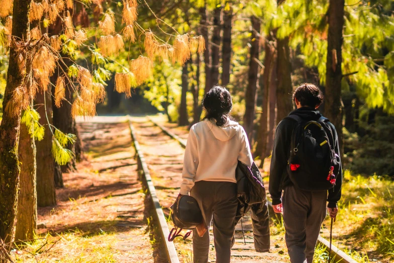 two people are walking down a path by some trees