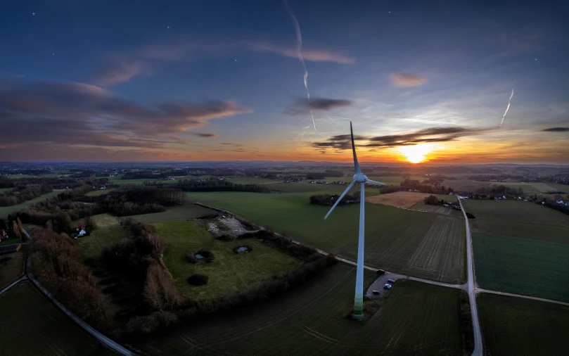 windmills standing in a field with a sunrise in the background