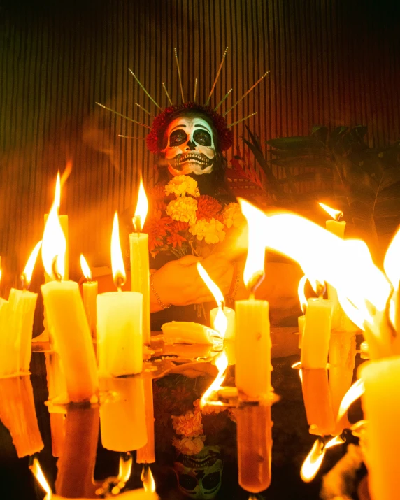 a man sitting behind a bunch of burning candles