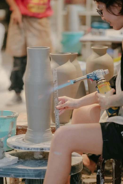 a woman painting a vase on a large table