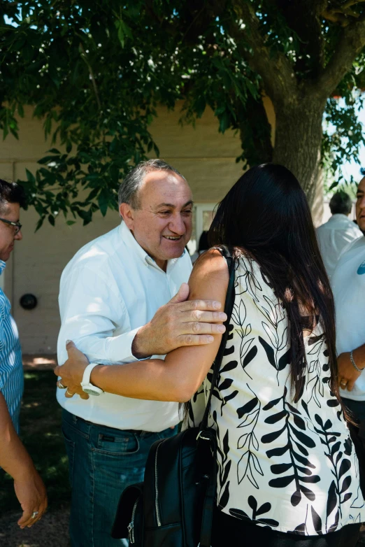 a man and woman hug as a crowd of people watch