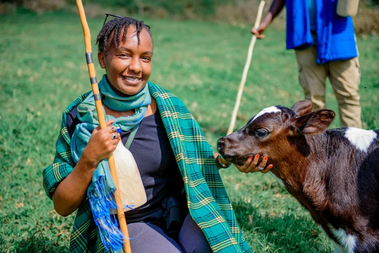 a woman smiles as she holds the stick to a cow's mouth