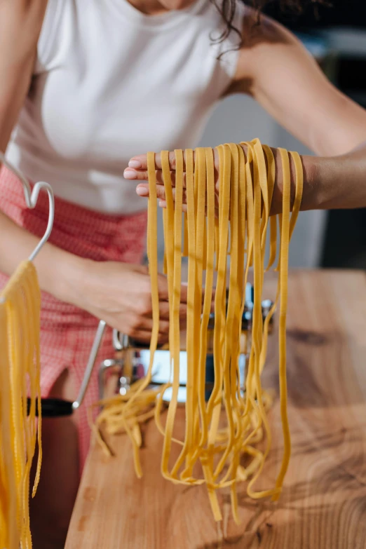 a woman standing over a table making pasta