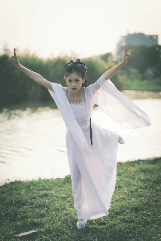 a woman is standing in the grass next to a body of water