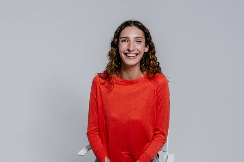 the young woman is standing wearing a bright red top