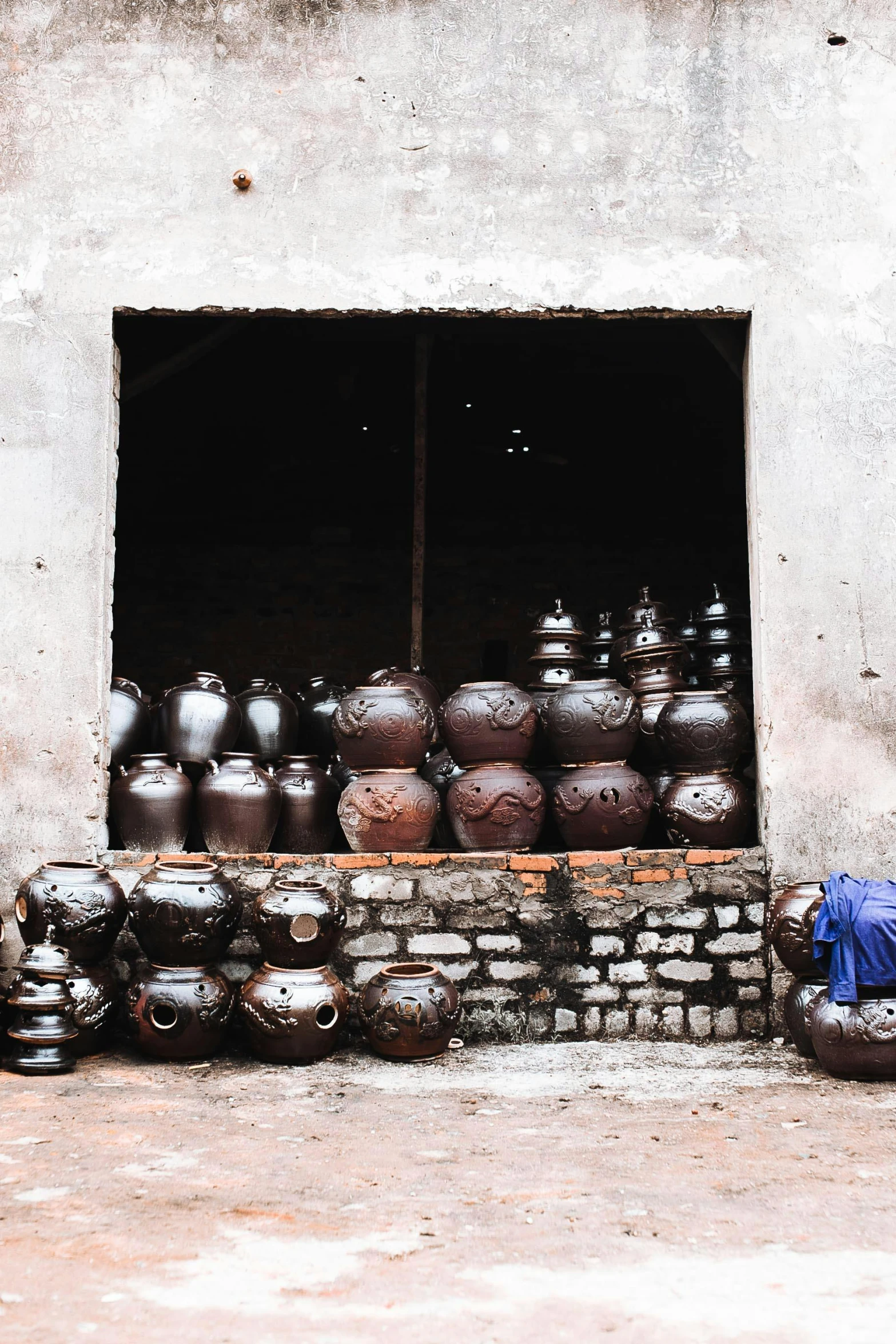 two men standing outside of a building filled with pots