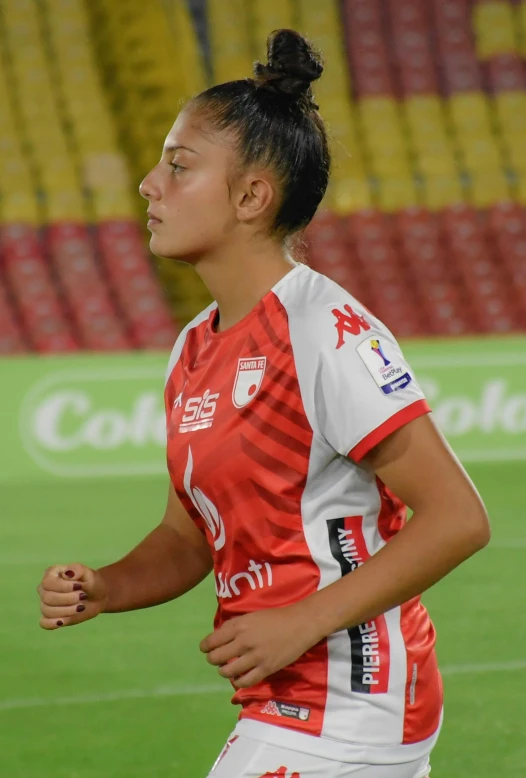 woman in red and white uniform holding soccer ball