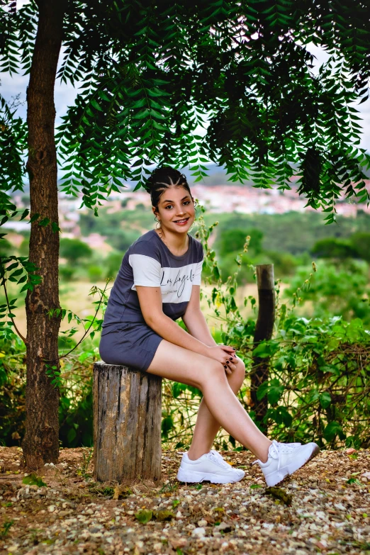 a smiling woman posing on top of a stump