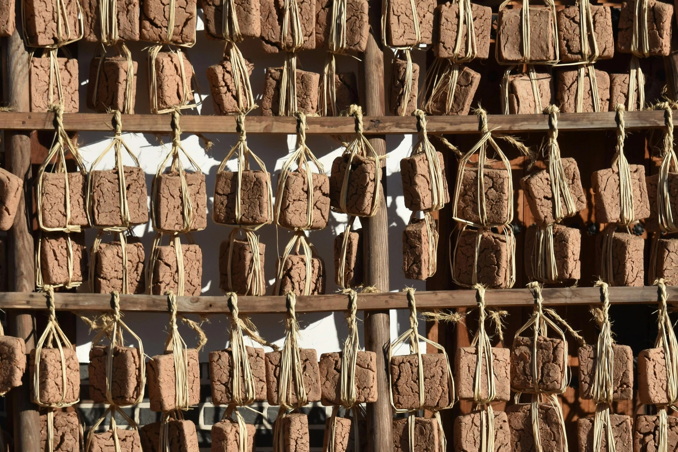 a wall with many bundles of wood hanging on it