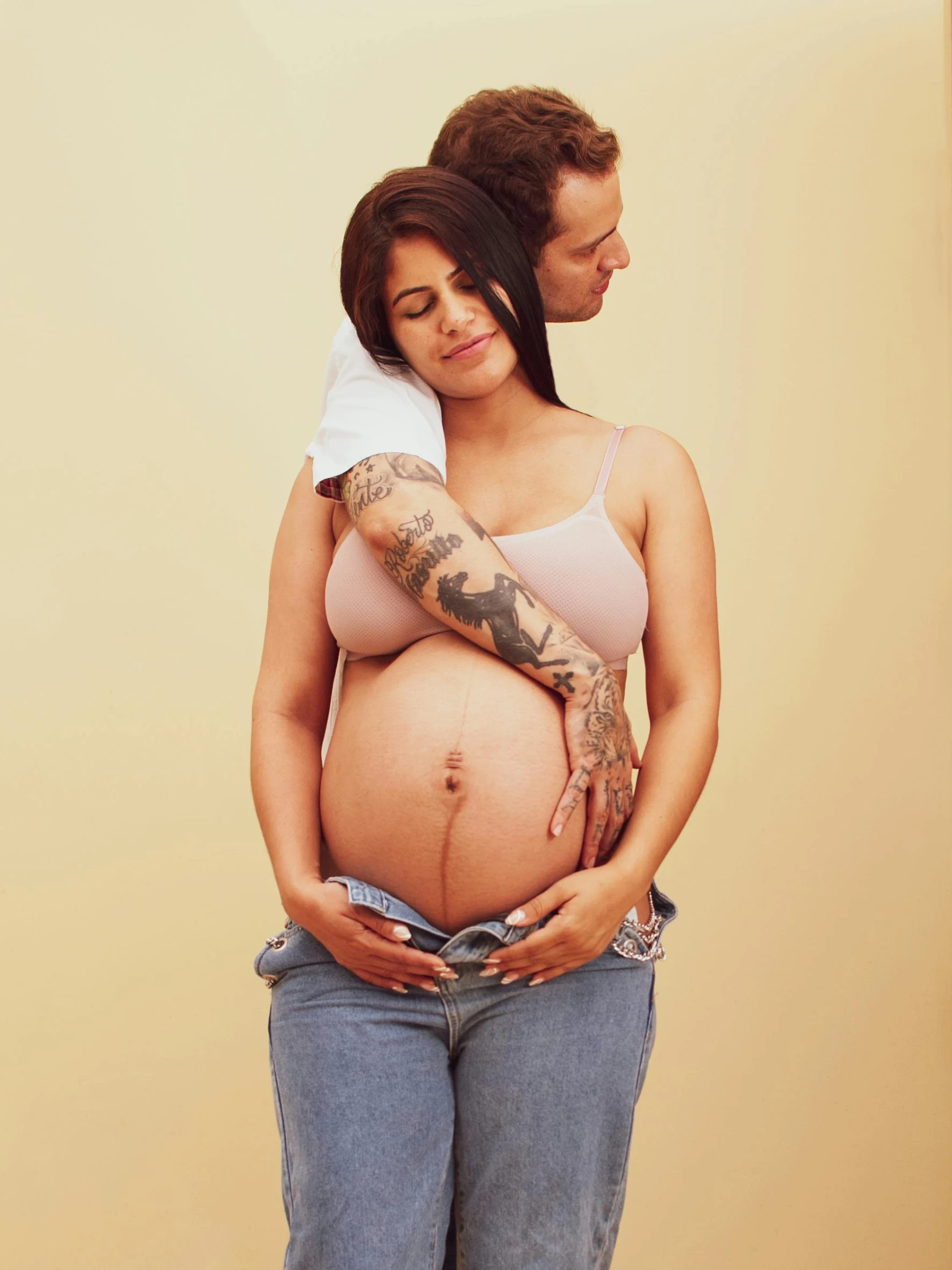 a pregnant woman poses next to her husband