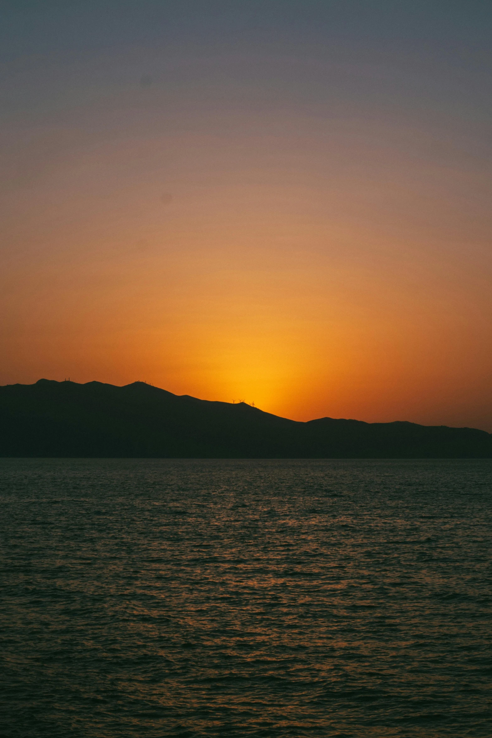 sunset at sea with mountains in distance