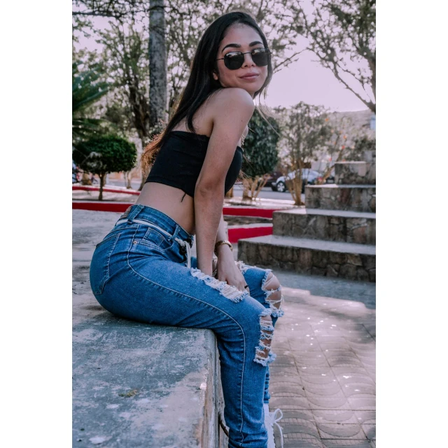 a young woman is sitting on the ledge of a wall