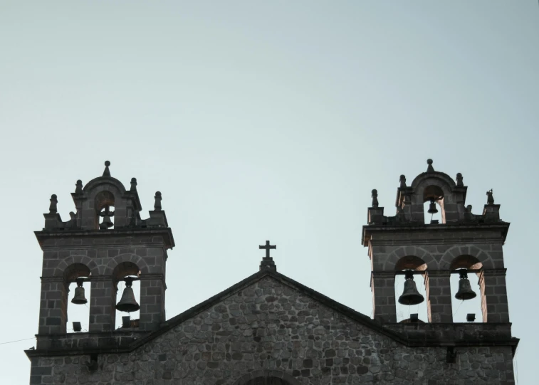 two bell towers with bells in front of a gray building
