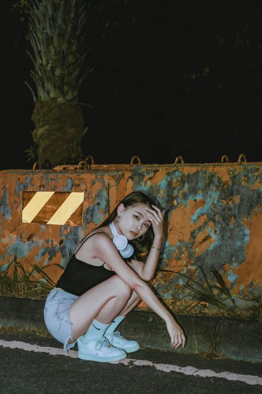 a woman kneeling on the curb, with her hand on her head