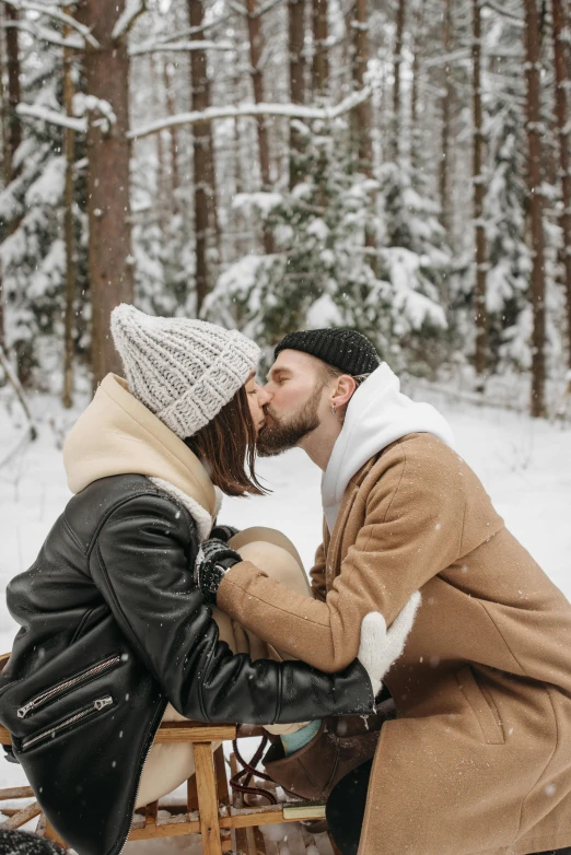 a man kissing a woman while she is snow covered