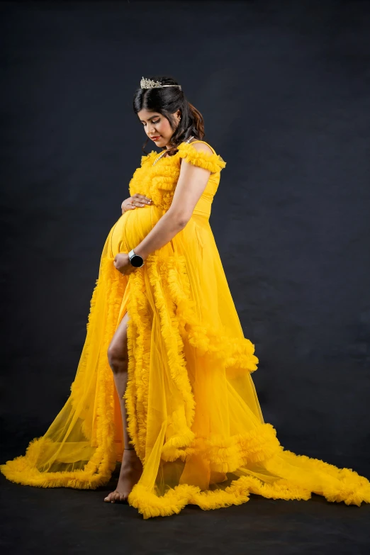 pregnant woman dressed in yellow standing with belly bump