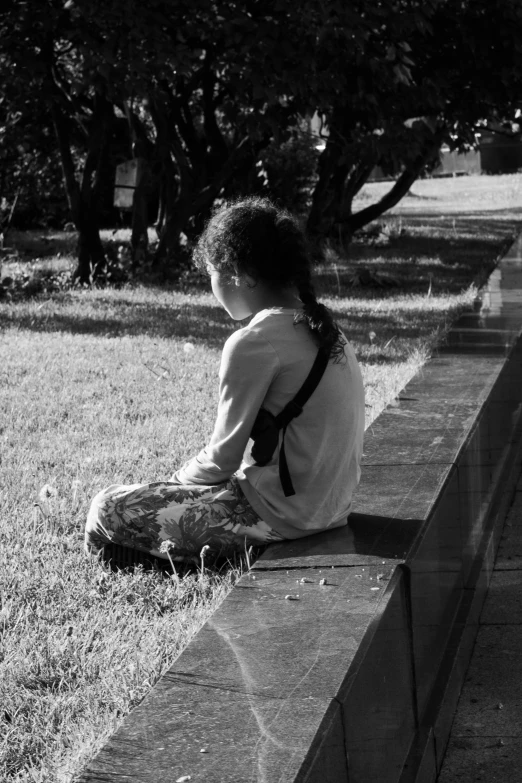 a young child sitting on the edge of a wall in the park