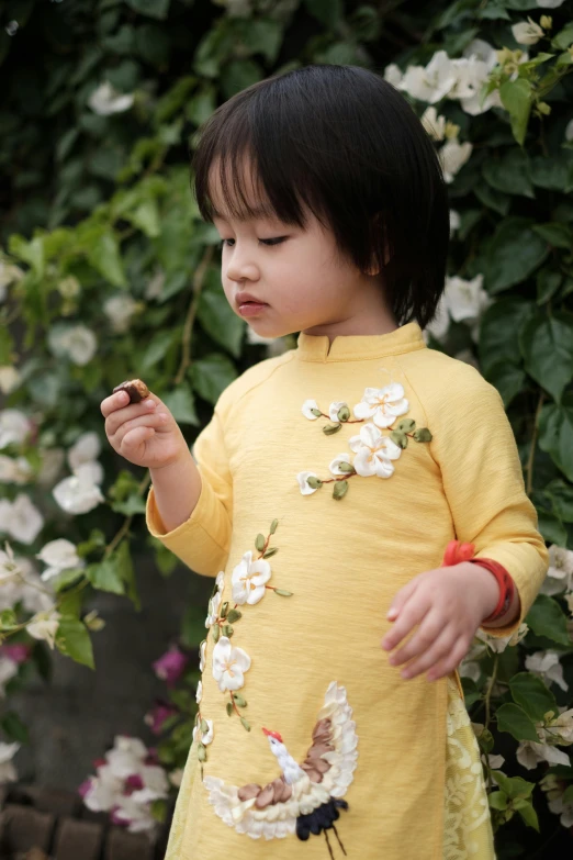 a little girl in yellow holding soing in her hand