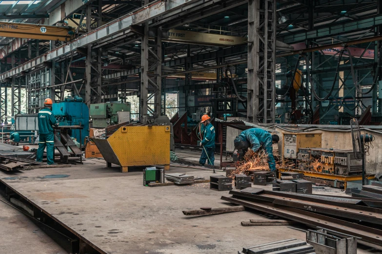 some metal workers working in a large steel factory