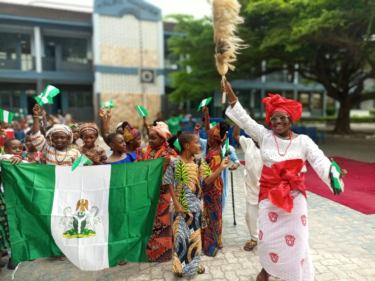 a group of women dressed in african clothing stand around each other with green flags