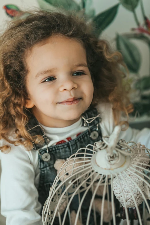 a smiling girl holding a white birdcage