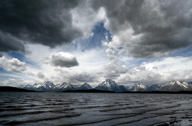 dark clouds and snow over an expanse of water and mountains