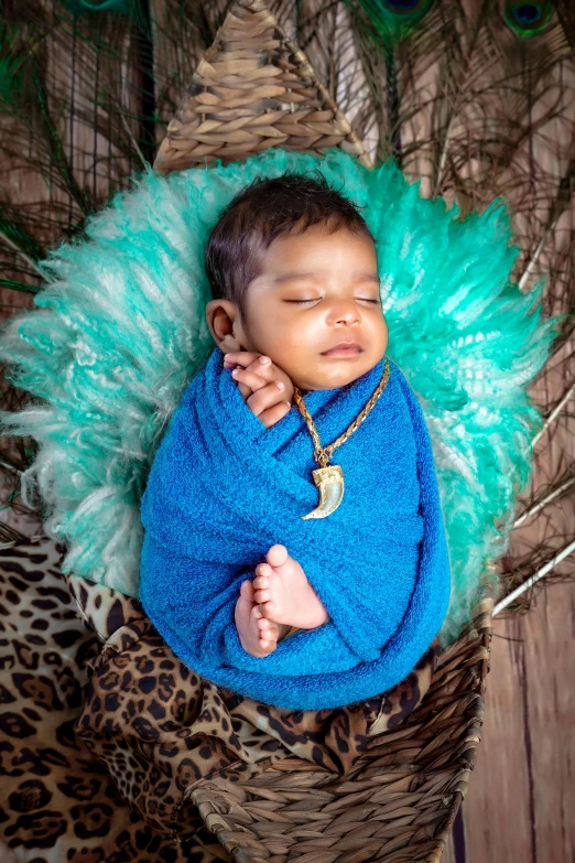 a baby wearing blue is laying in an elaborate blanket